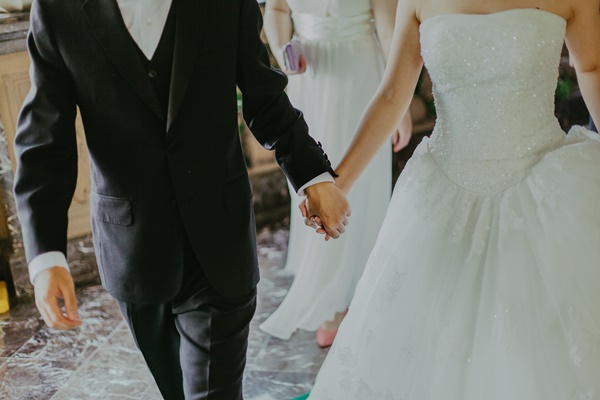 50-woman-wearing-white-wedding-gown-holding-hands-with-man